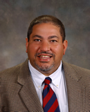Dr. Michael Salcedo smiling in a brown suit