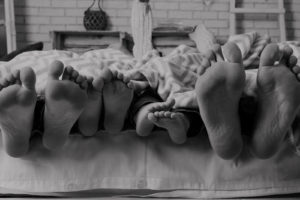Family with healthy feet laying in bed together